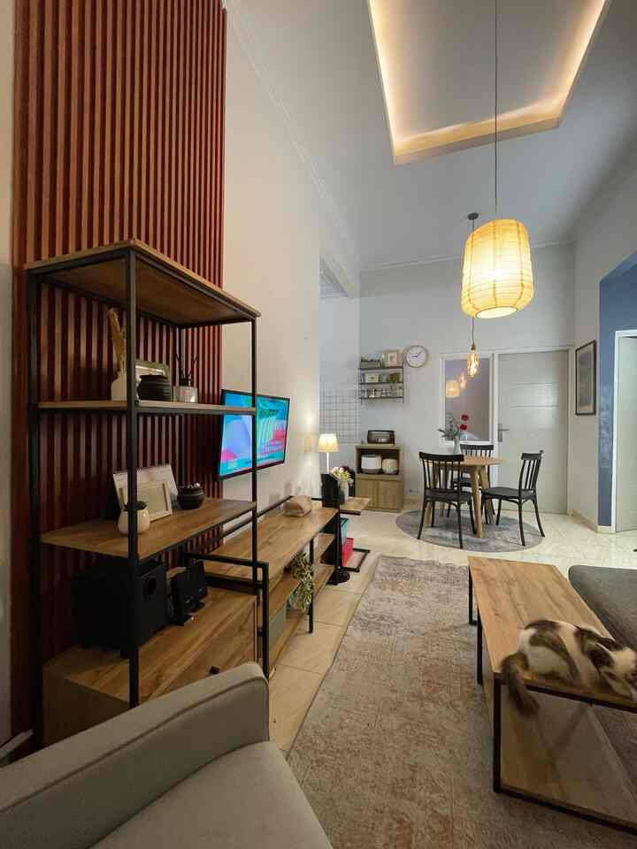 Brown wood tones and white walls define a cozy living and dining room for four featuring pendant lighting and a cat on the coffee table