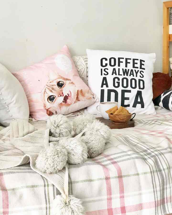 Pink and white toned bedroom featuring cat-themed cushions and coffee setup creating a cozy home cafe atmosphere