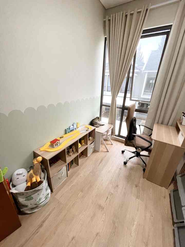 Natural beige-toned small room featuring a cozy home office with a desk and office chair by the window and children's toy storage