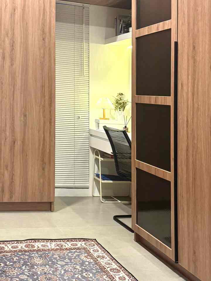 Wood tone wardrobes in a small room featuring a white desk and black office chair for a cozy home office setup