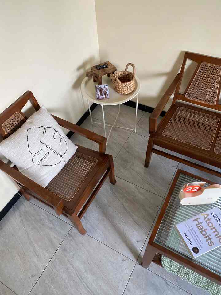 Natural-toned small living space featuring wooden armchairs and a white side table arranged in a vintage style setting