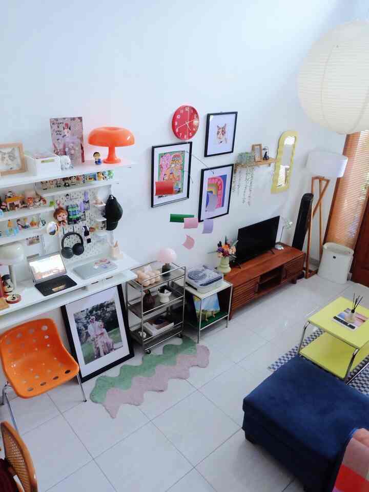 Bright white-walled mid-century modern living room with an orange chair and colorful decorative accents, creating a lively atmosphere