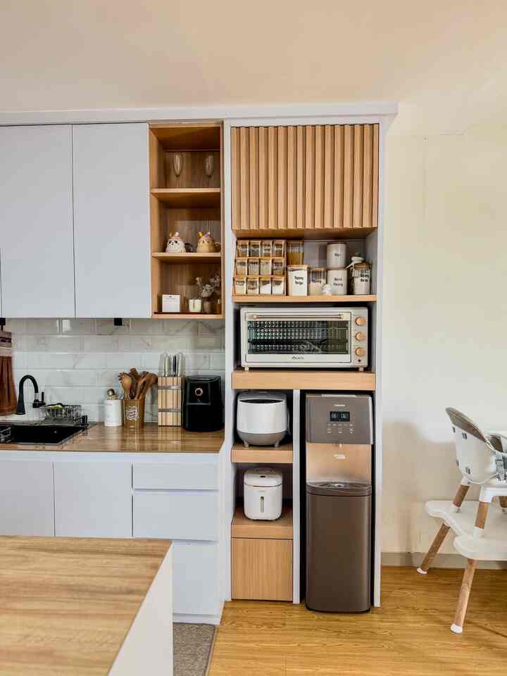 Clean kitchen space with white and wood tones featuring organized storage containers and a water dispenser in a modern kitchen interior