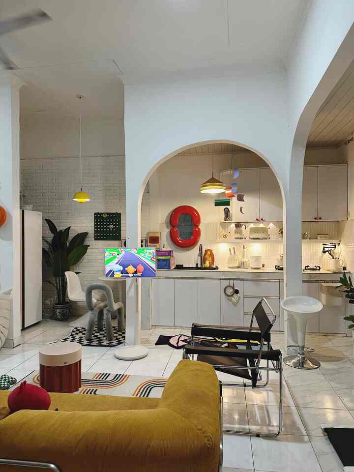 White and yellow toned living room and kitchen space featuring a mustard sofa and arched doorway, presenting a modern and cozy interior