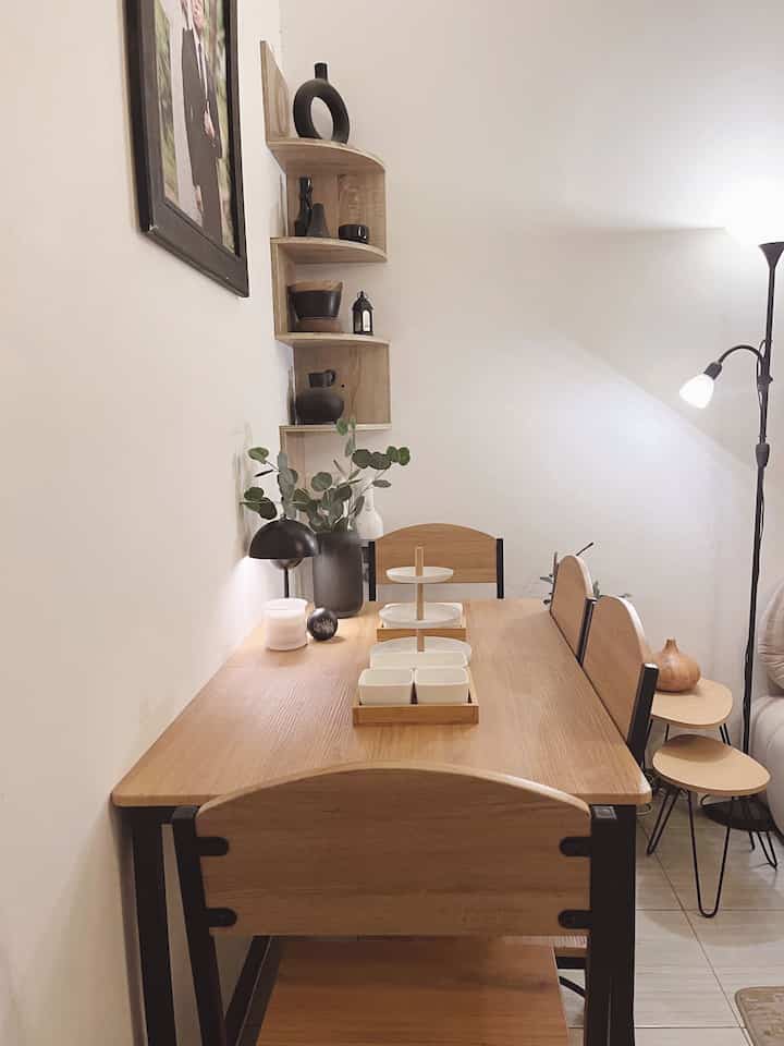 Warm wood tone and black accented 4-person dining room featuring corner wall shelves and floor lamp creating a cozy ambiance