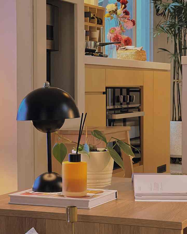 Cozy living room and kitchen area with natural wood tones featuring a black table lamp and orange diffuser on the wooden table