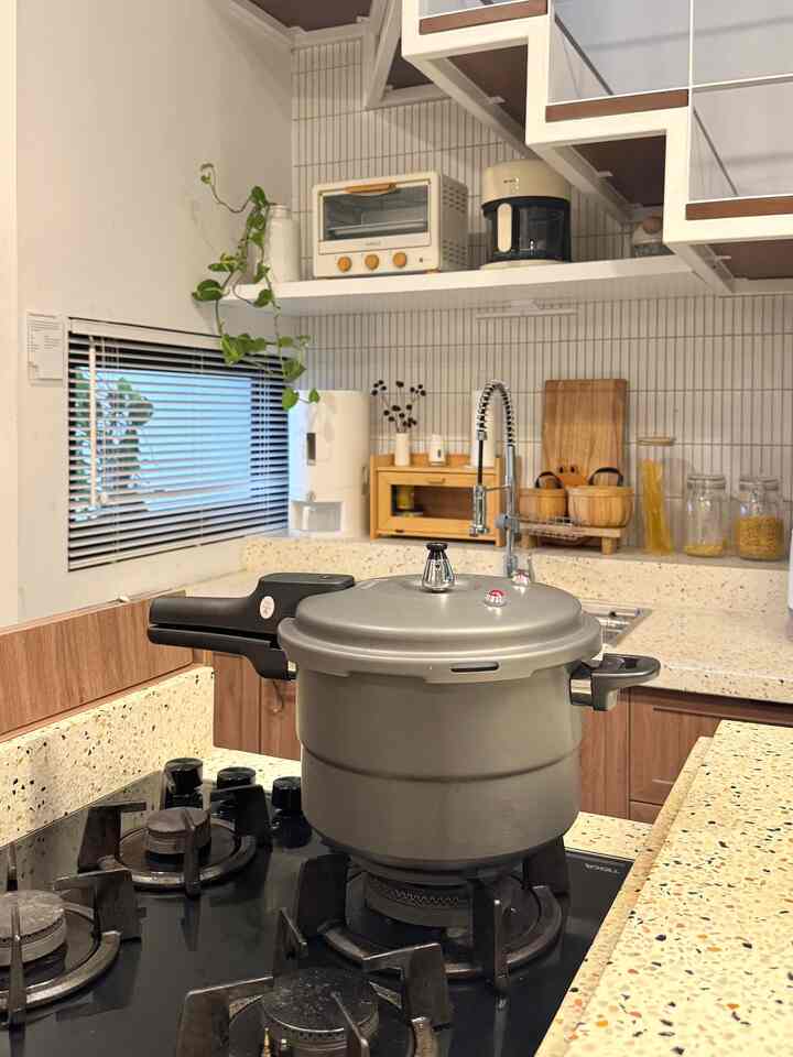 White and wood-toned kitchen featuring countertop and gas stove with a pressure cooker, creating a cozy atmosphere