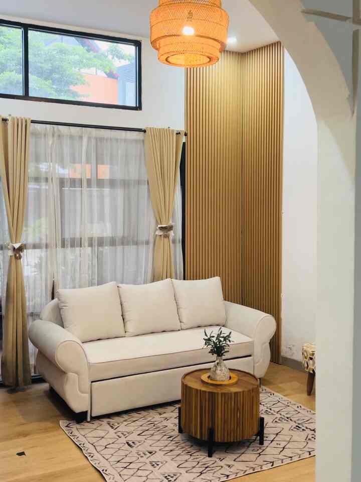 Beige and wood tone living room featuring a beige sofa and round wooden coffee table centrally placed, creating a cozy atmosphere