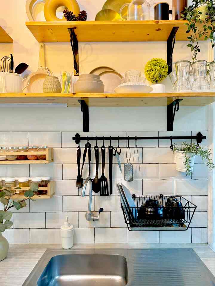 Clean kitchen sink area with white tiled backsplash and black hanging storage utensils