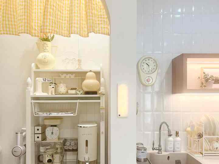 Bright white and beige toned arched kitchen space featuring vintage wall clock and organized storage shelves for a clean kitchen look