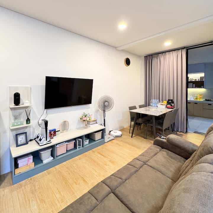 Modern living and dining room with natural wood flooring and brown sofa recliner, featuring clean lines and open layout