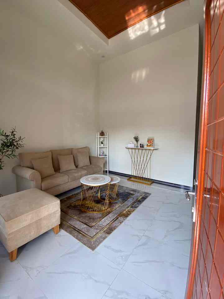 Modern living room in warm beige and gold tones featuring a beige sofa and round coffee tables in a simple setting