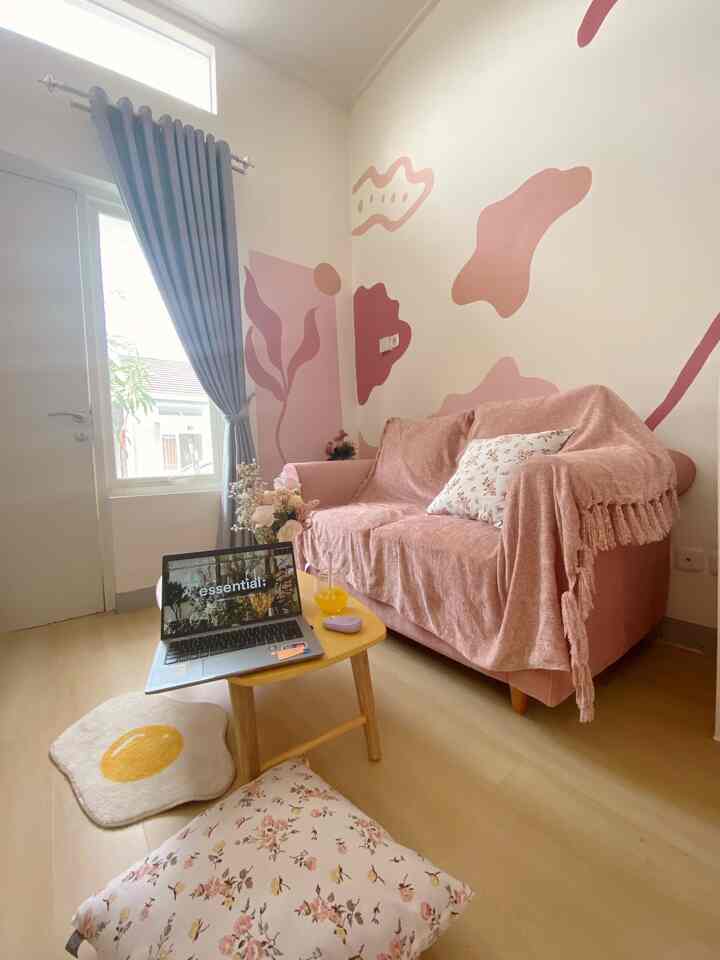 Small living room with pink sofa and gray blackout curtains, featuring laptop and drink on wooden table in a natural cozy setting