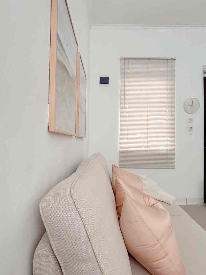Bright white and beige living room featuring a beige sofa with pink cushions, simple and airy atmosphere