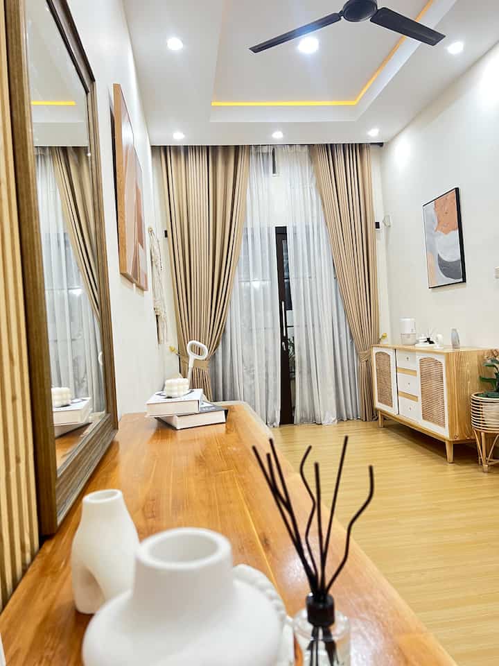 Beige and wood-tone living room featuring curtains and large mirror with warm natural ambiance