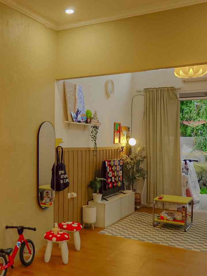 Beige-toned living room with natural light from window, TV stand, and red children's stools creating a cozy atmosphere