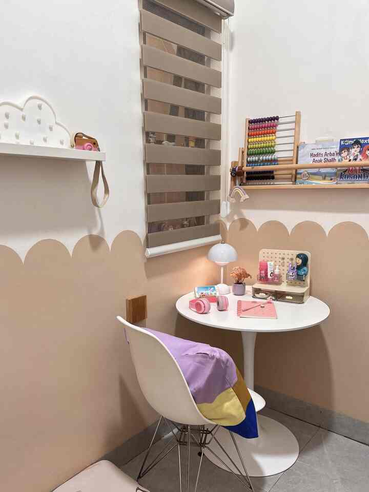Bright white and beige toned small kids' room corner featuring a child’s desk and toys in a cozy space
