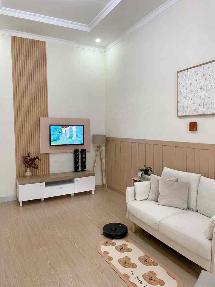 White and beige toned living room featuring a white sofa and TV stand, creating a clean and modern atmosphere