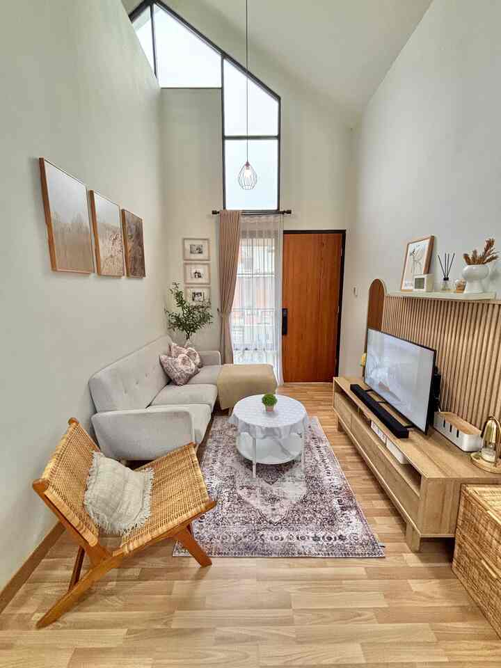 Bright living room with white walls, wood-tone flooring, high ceiling, big window, featuring a gray sofa and round coffee table in a natural atmosphere