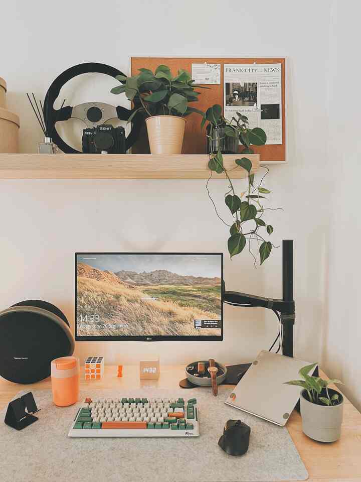 Clean home office space with white walls and light wood desk featuring a computer monitor and keyboard