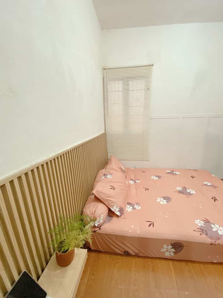 White walls with wood slatted paneling, pink floral bedding bed in a 6-tatami sized bedroom