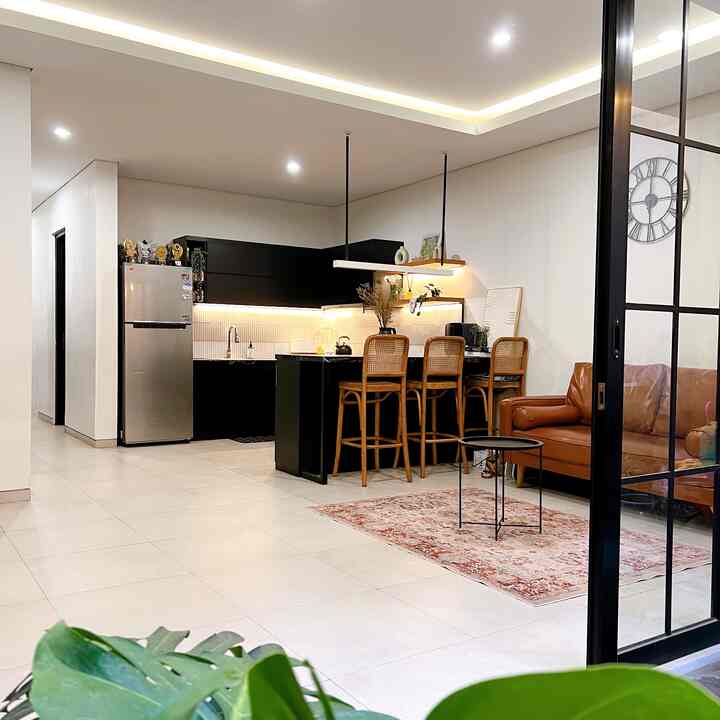 Modern living room with white and black kitchen, brown leather sofa, and red carpet creating cozy atmosphere