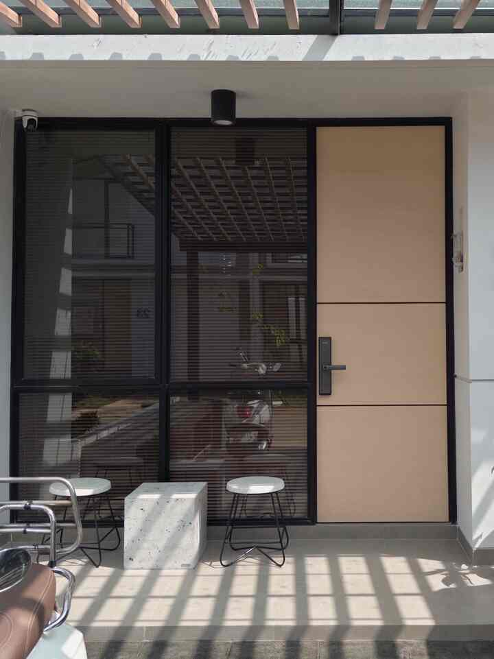 Beige entrance door with black blinds creating a simple, modern entrance space
