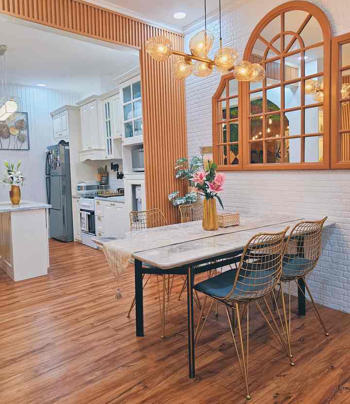 Brown and white toned dining room and kitchen featuring gold pendant lights and dining chairs, creating a modern and natural interior