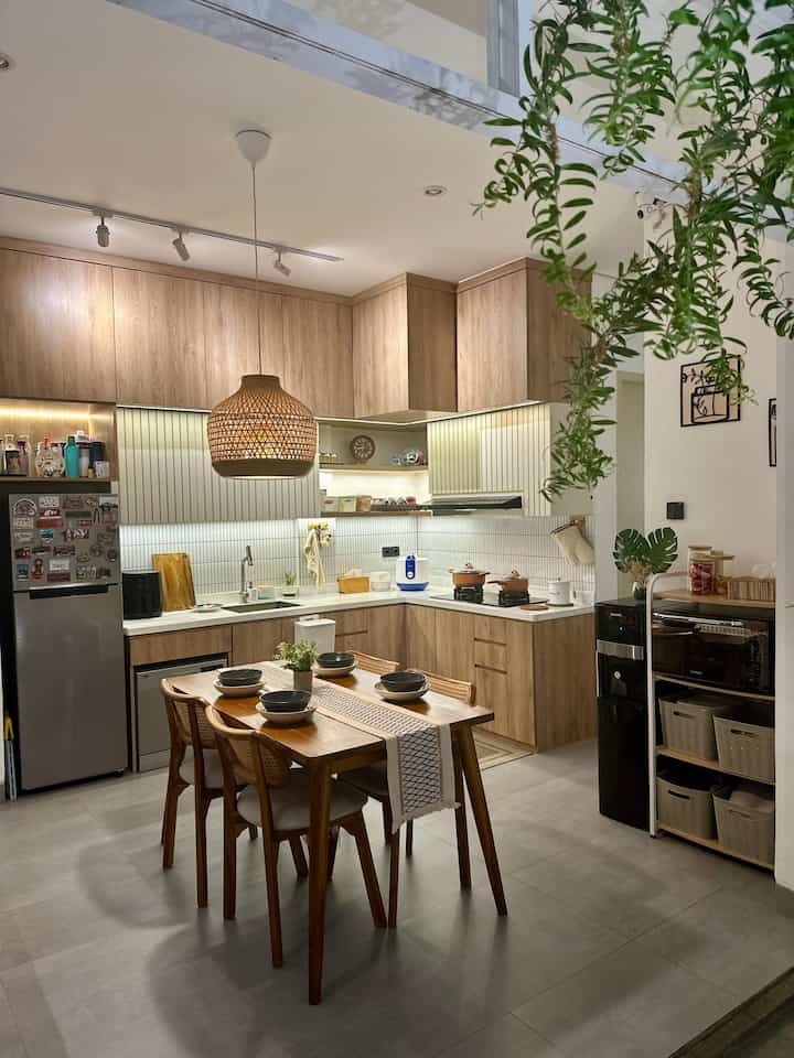 Brown and ivory toned kitchen and dining room featuring wooden table and rattan pendant light in a natural style space