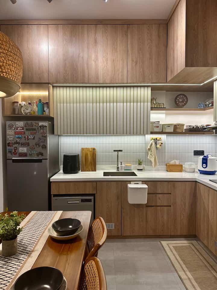 Natural tone kitchen space featuring wood cabinets, dining table, and clean white countertop with cozy atmosphere