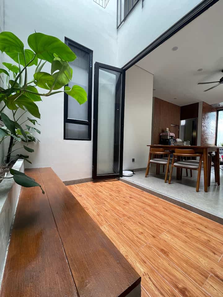 Wood tone flooring and bench on balcony space, with dining table and plants giving a natural atmosphere