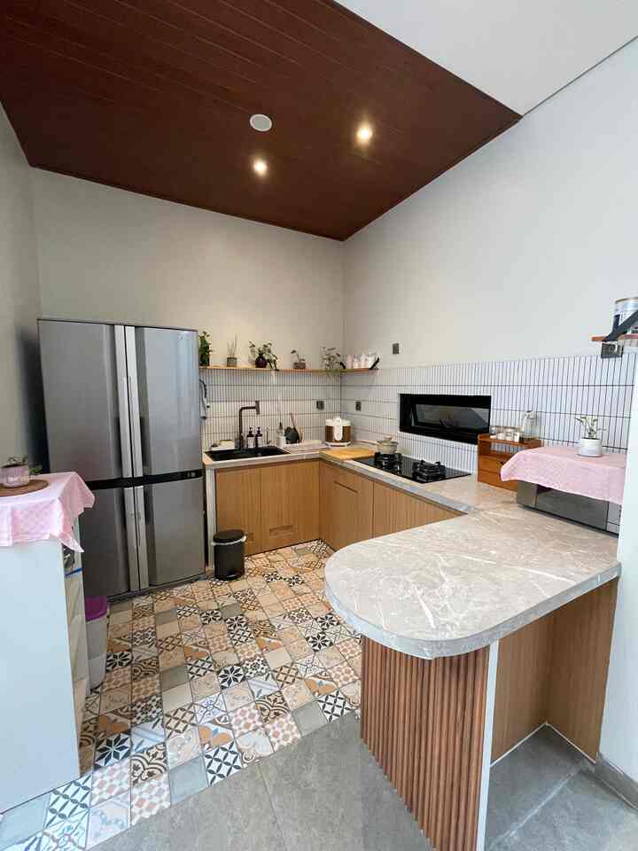 Natural-toned kitchen with wooden ceiling and colorful patterned tile floor, featuring wood cabinets and marble countertops