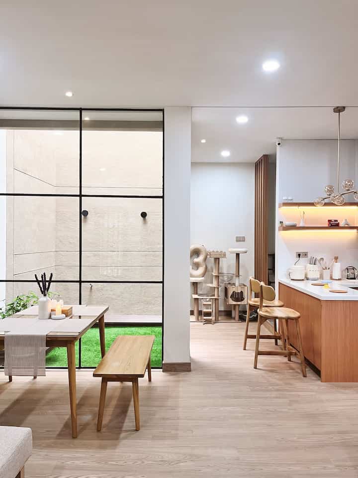 A white and brown natural modern dining room and kitchen with wooden furniture, featuring a cat tower for pet living