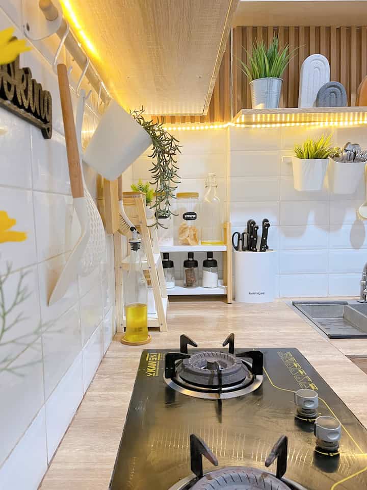 Cozy kitchen space with white tiled backsplash, wood-tone shelves and countertop, and black gas stove