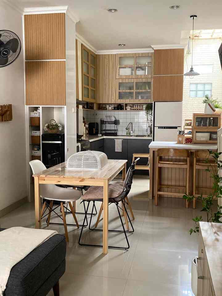 「限られたスペース、無限のスタイル：キッチンとダイニングのインスピレーション」

ダイニングルームと組み合わせたこの小さなキッチンは、美しく効率的に装飾できます。この家には 5 人の住人が住んでいるため、ダイニング チェアが 4 脚以上必要になります。そのため、キッチン アイランド テーブルとバー チェアが 2 脚あります。 

L字型のキッチンは、調理場（コンロ）、調理台、洗い場（シンク）、冷蔵庫など、スペースの隅を食品の保管場所として最大限に活用します。 

このキッチンは、既存の予算に合わせて何度か改装されました。 2016年に最初のキッチン（最後のスライド）が完成し、2024年に最初のスライドに変更されました。完成まで8年かかりました。

これは、キッチンのデザインを白からダークグレーと組み合わせた木材に変更したものです。低予算での変更方法の 1 つは、キャビネットの裏地のみを交換し、アイランド テーブルも PVC 裏地で覆って新品同様の外観にすることです。 

新鮮に見えるように、装飾として小さな緑の植物を飾り、装飾的な吊り下げライトを設置します。スパイス、食品、医薬品を保管するための棚が付いています。 

📌 キッチンセットの素材は、多重 HPL タコ層と PVC 内部フィルムコーティングを組み合わせたものです。上部のキャビネットには、ヘムロックとヴィラートウッドのモチーフをあしらった紙コーティングを使用し、下部のキャビネットにはタコミッドナイトグレー TH 006 AA HPL コーティングを使用します。
📌 キッチンのカウンタートップには、大理石モチーフの花崗岩タイル（インフィニティ カサブランカ ブランド、光沢のあるグレー、サイズ 60 x 60）が使用されています。
📌 アイランドテーブルは、白いトラバーチンをモチーフにした PVC インテリアフィルムで覆われた古いキッチンテーブルの花崗岩で作られています。
📌 Wegenブランドの2穴ステンレスシンク。
📌 プレカット セラミック バックスプラッシュ 30x30 (10cm 四方) Ellagress ブランド。

#hpltaco #mejadapur #granittile #sinkstainless #keramikprecut #lampugantung #mejamakanminimalis #kitchenset #dapurmungil #dapurminimalis #makeoverdapur #stylingdapur #dapurimpian
#低予算の改装 #naturalkitchen #mejaisland