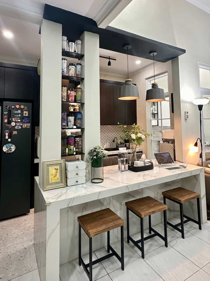 Compact kitchen-dining room in white and black tones featuring marble countertop and wooden stools with a modern, clean atmosphere