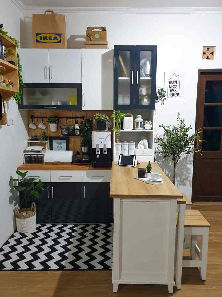A minimal black, white, and wood tone mini pantry and dining space featuring a kitchen island table and organized cabinetry with a warm atmosphere