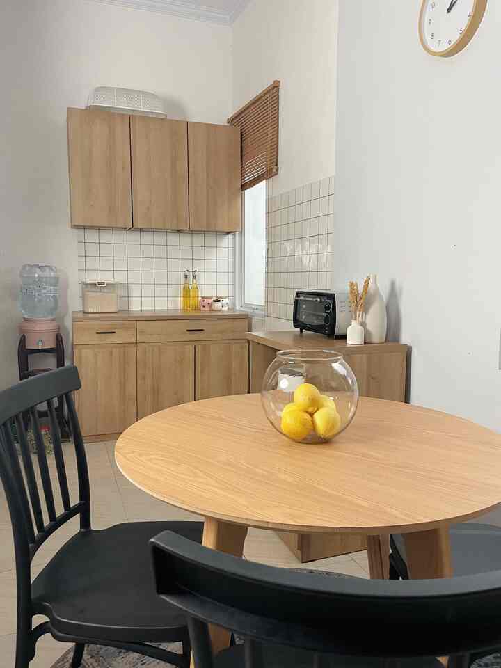 Bright wood tones and black chairs in a minimal dining and kitchen space, simple and warm atmosphere