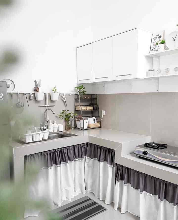 Modern kitchen in white and gray tones featuring L-shaped countertops and upper and lower cabinets with a clean layout