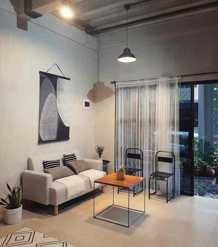 Natural-toned living room featuring a beige sofa, wooden coffee table, curtains, and plants creating a cozy atmosphere