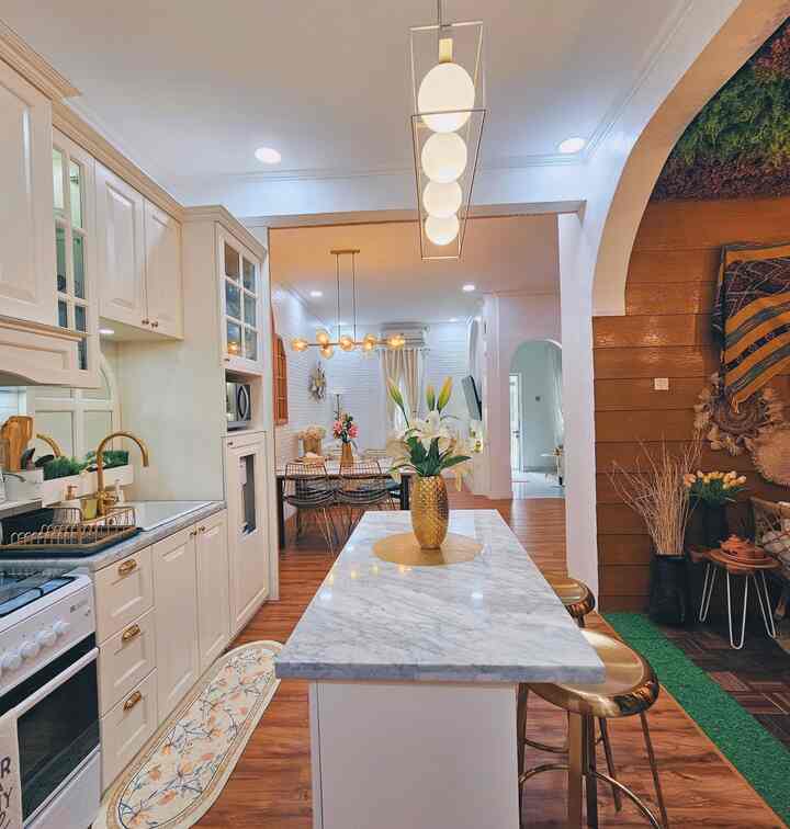 White and wood tone kitchen and dining room featuring a marble dining table with gold bar stools at the center, creating a cozy atmosphere
