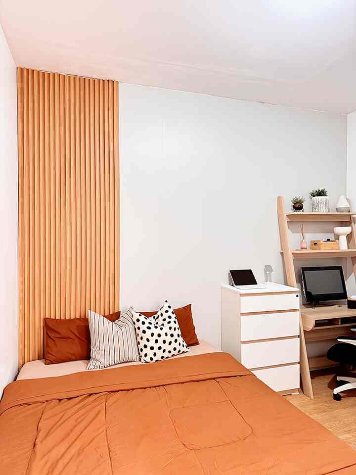 White and wood-tone two-person bedroom featuring orange bedspread and desk with a cozy atmosphere