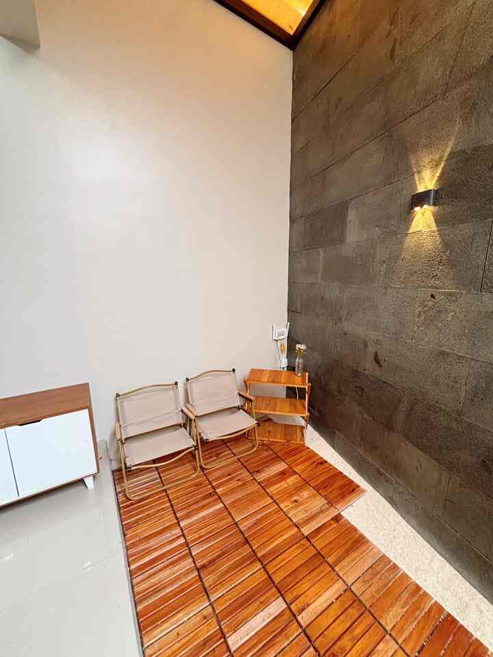 Small space featuring black stone wall and wood tone decking with corner storage and foldable chairs for cozy indoor seating