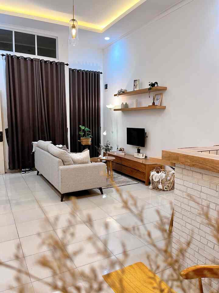 Natural style living room with white walls and wood tone furniture, featuring beige sofa and brown curtains creating a cozy atmosphere