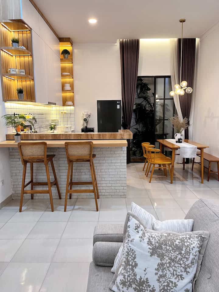 Modern open space kitchen and dining room in white and brown tones featuring gold pendant lighting in a compact layout