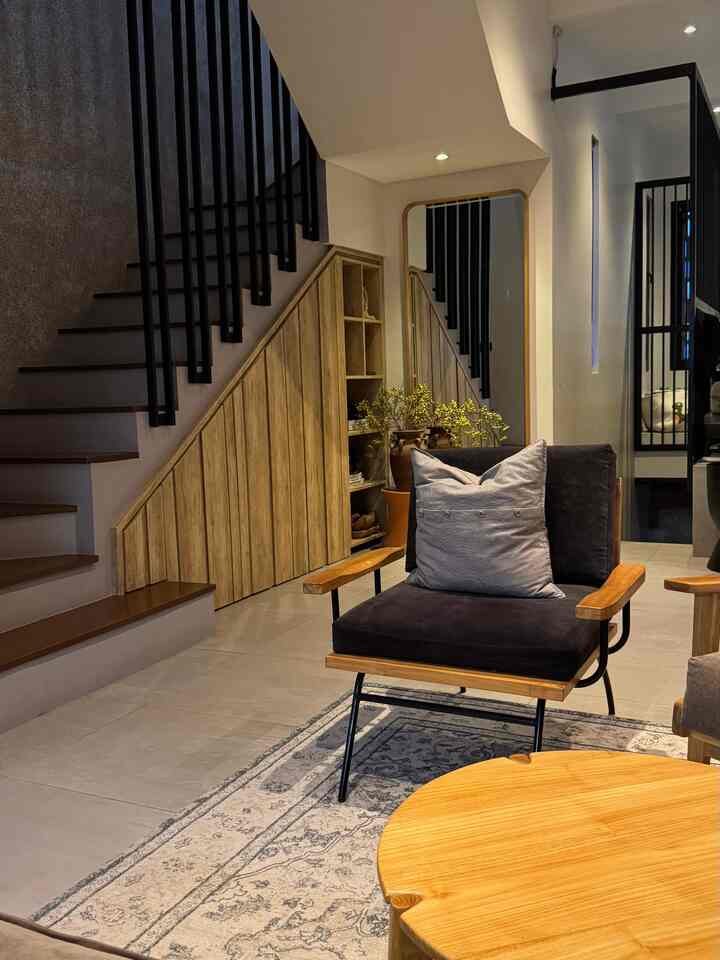 Natural modern living room featuring wood tones and black accents with wooden armchair, rug, and large mirror