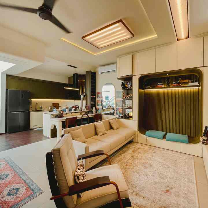 A khaki and beige toned living room and kitchen space featuring a large sofa and armchair with a warm modern interior