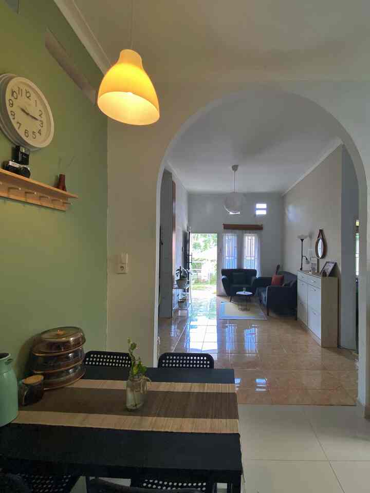 White and green toned open space living room and kitchen featuring an archway and simple dining table in a spacious area