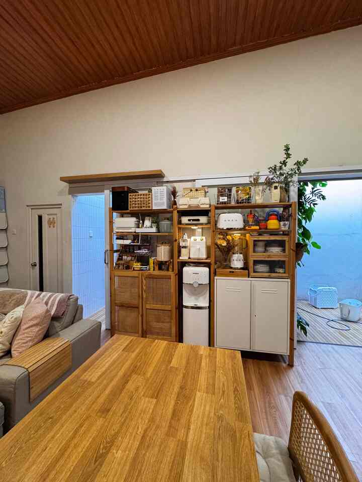 Natural color living and kitchen space featuring wooden dining table and cabinets with cozy interior atmosphere