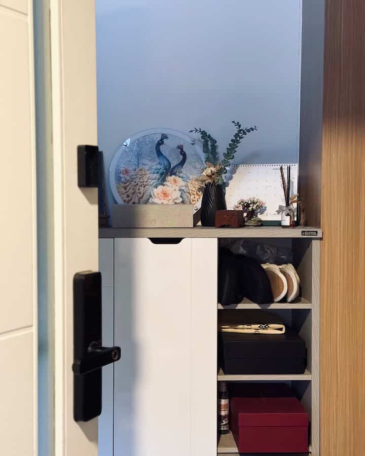 Neutral white and brown tone entrance featuring a storage cabinet with displayed slippers and a reed diffuser for a tidy look
